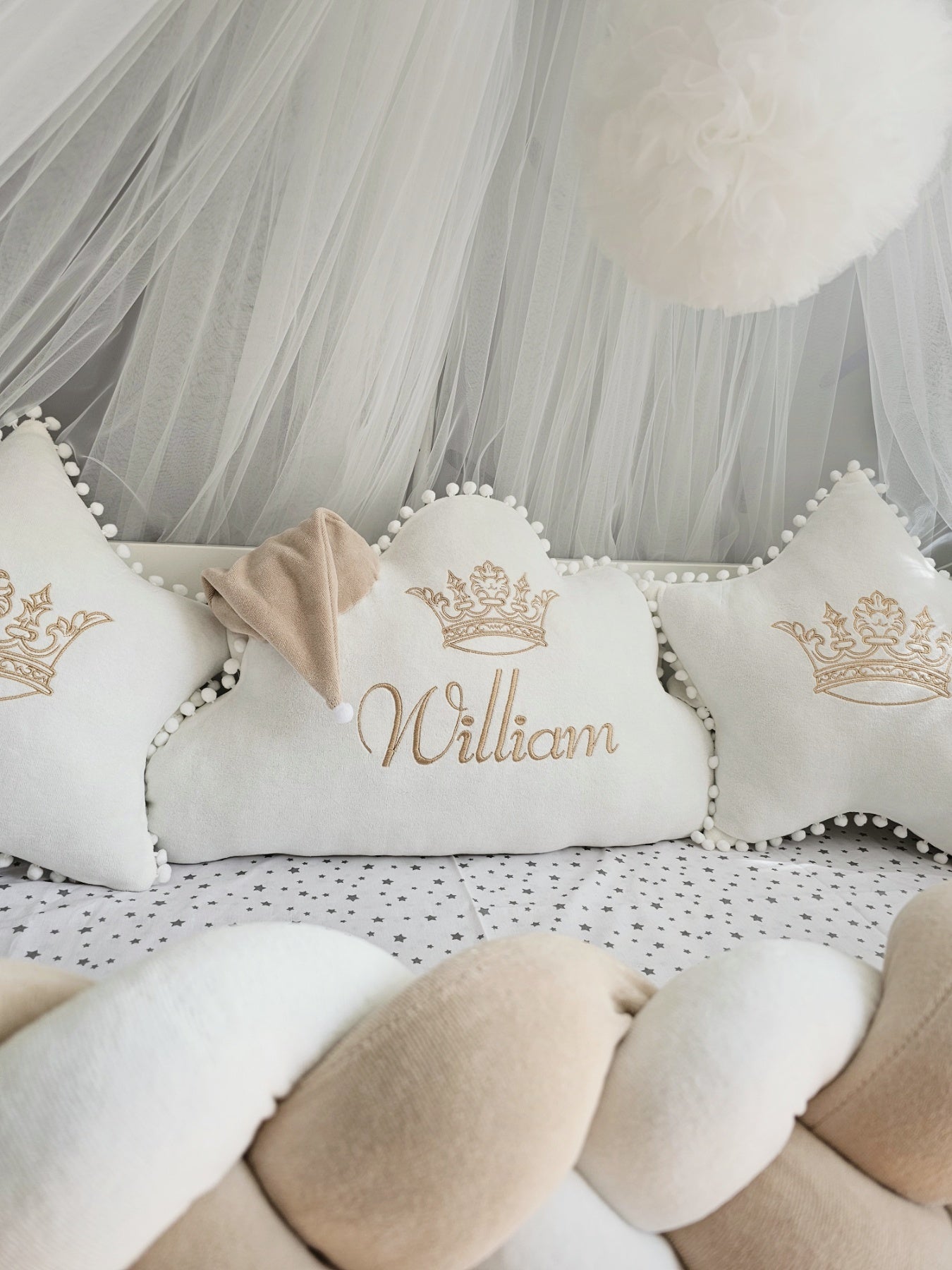 Decorative pillows with 'William' and crowns on a soft surface with tulle in the background.