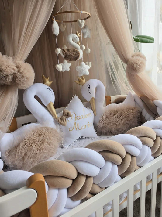 Decorative swan pillows and mobile in a crib with beige and white accents.