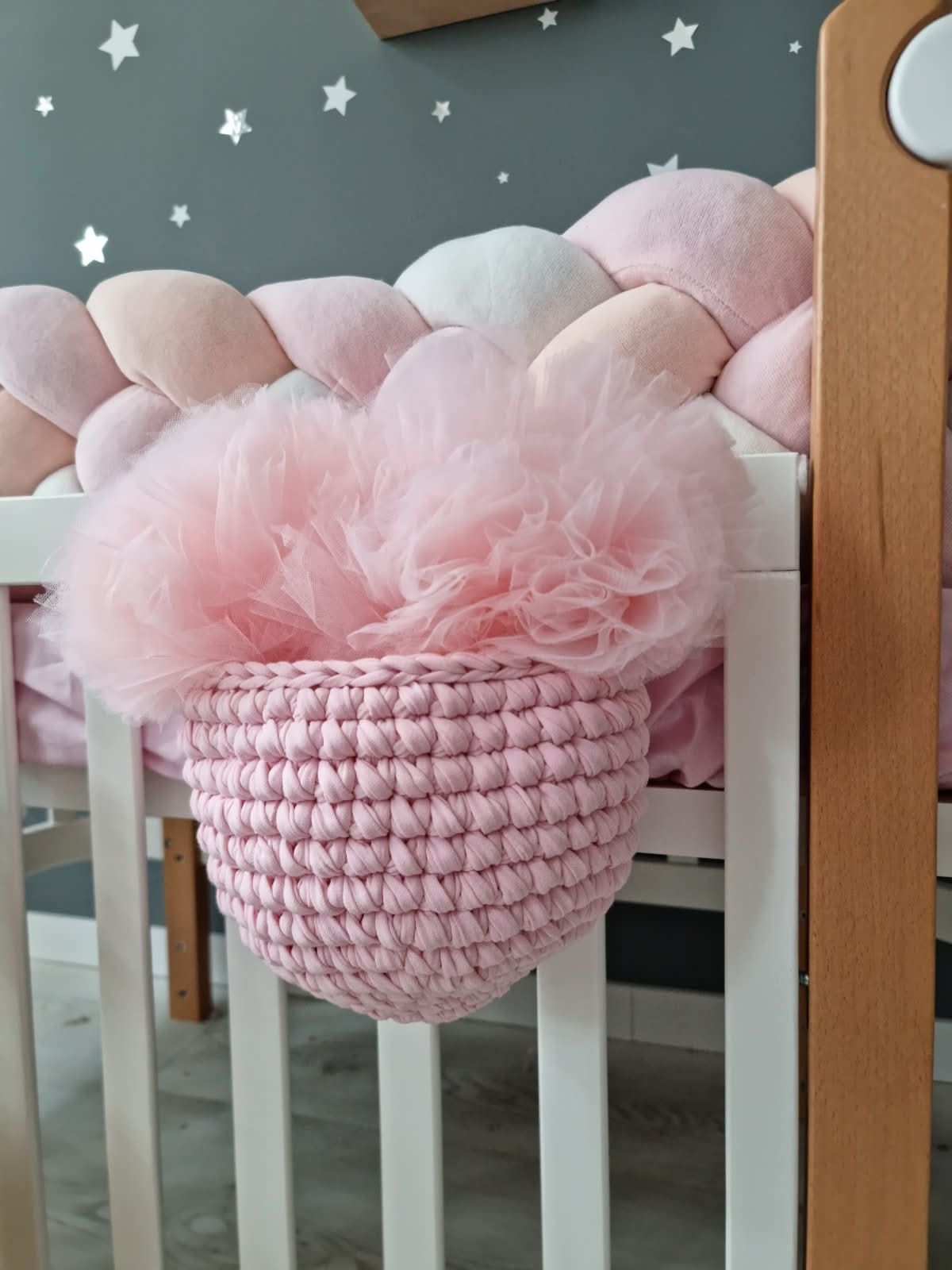 Pink crochet basket with tulle inside on a white crib