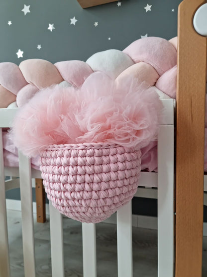 Pink crochet basket with tulle inside on a white crib