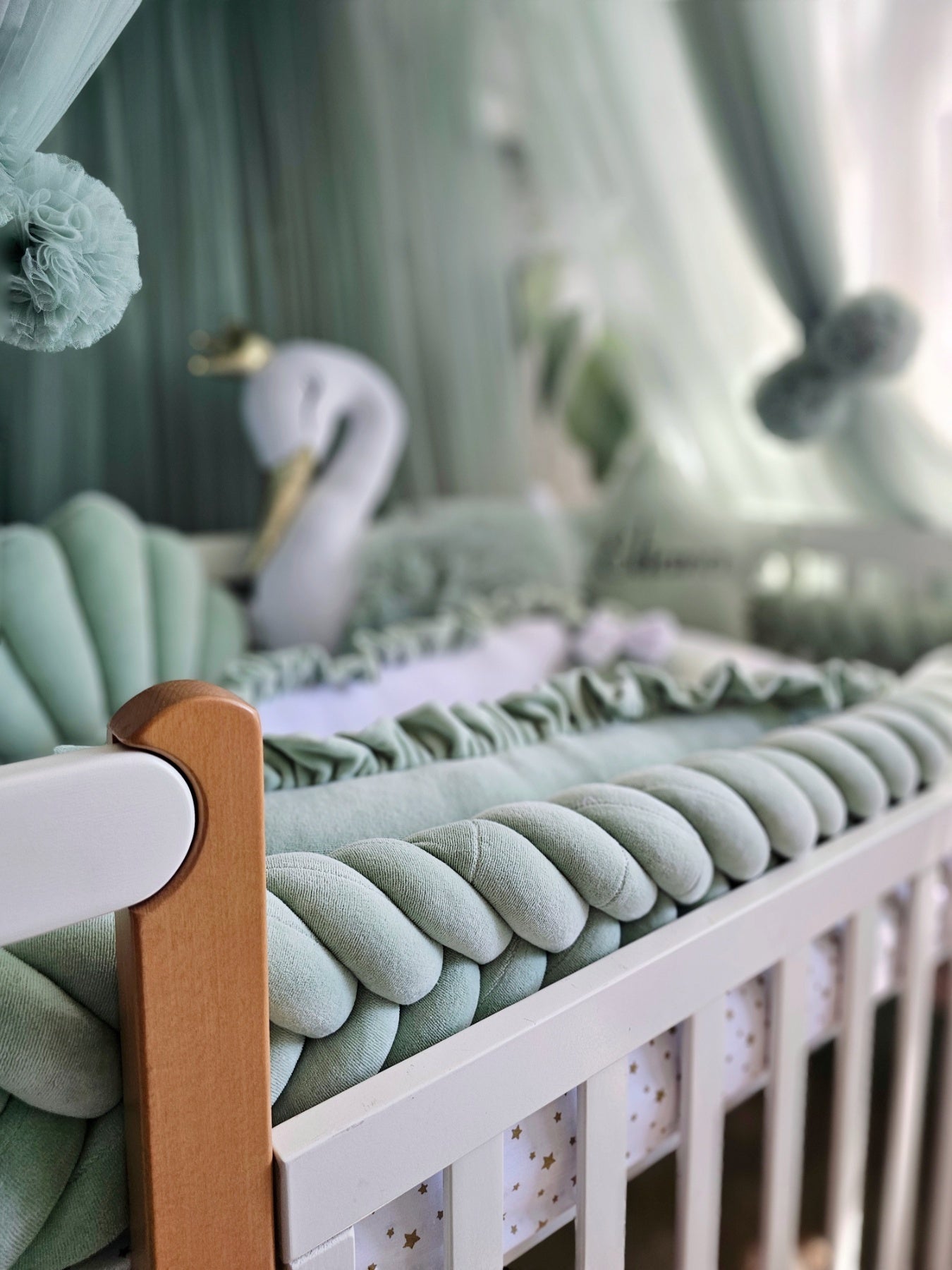 Crib with green bedding and decorative elements in a nursery setting