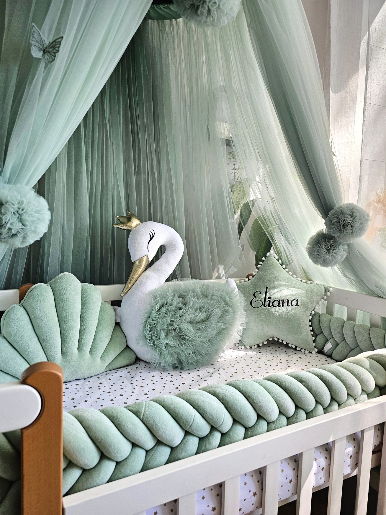 Children's crib with mint green bedding, swan decor, and personalized pillow.