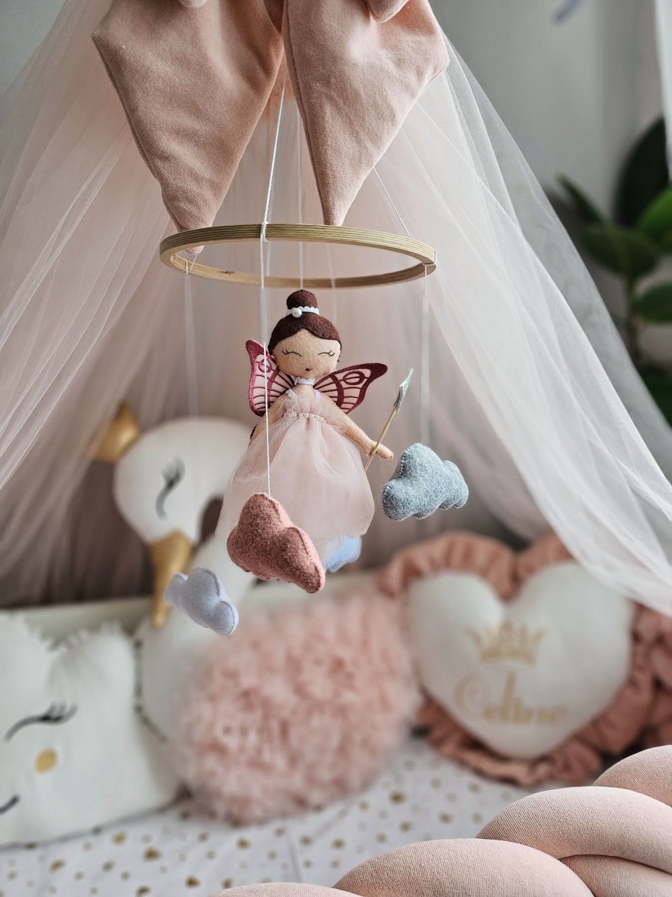 Baby mobile with fairy and cloud decorations hanging in a crib.