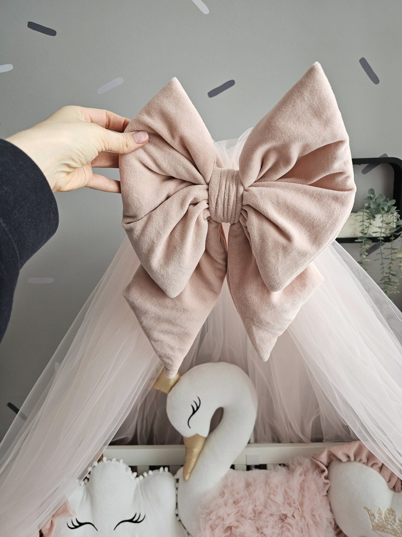 Large pink bow held above a crib with swan decorations.