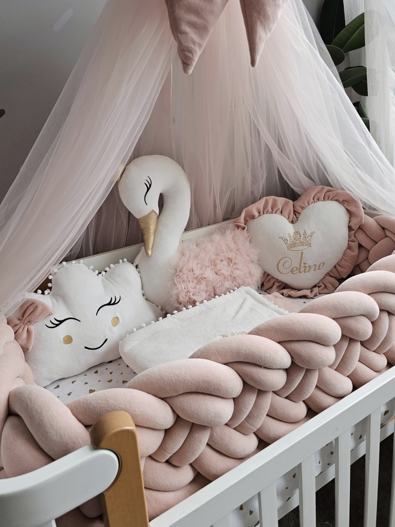Crib with pink and white plush toys and blankets in a nursery setting.