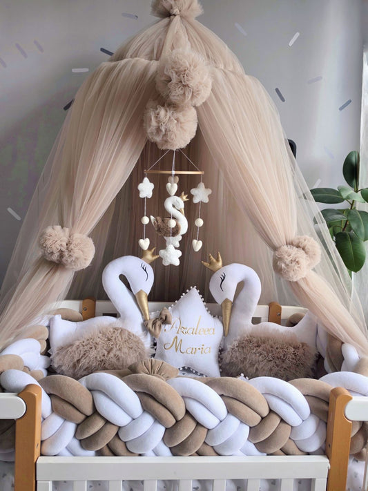 Nursery crib with canopy, swan decorations, and a mobile above.